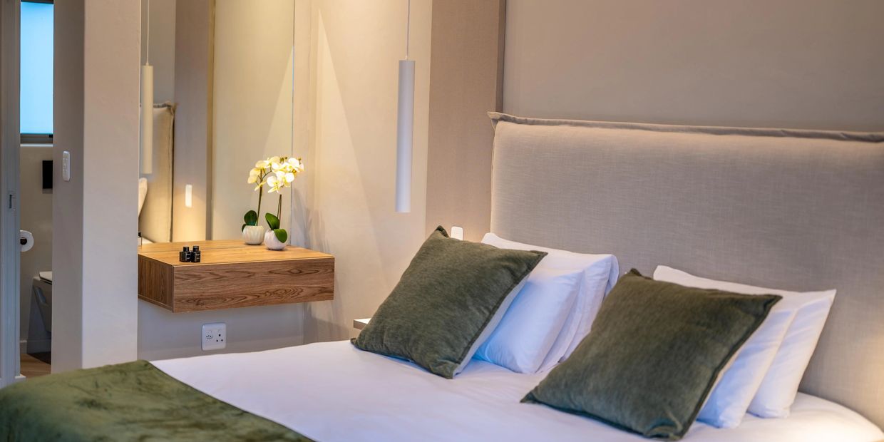 Cozy bedroom with white sheets and green pillows.