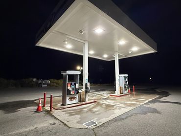 A deserted gas station illuminated at night with two fuel pumps.