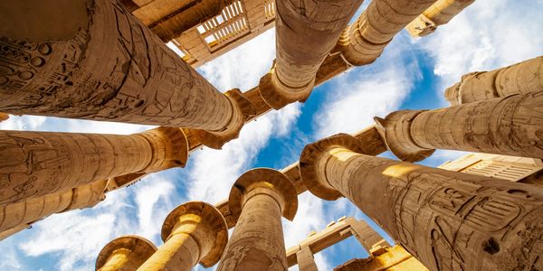 Ancient Egyptian columns with hieroglyphics against blue sky.