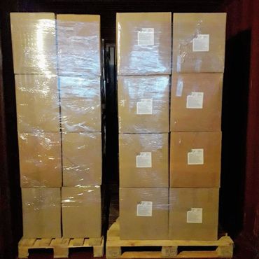 Stacked cardboard boxes wrapped in plastic on wooden pallets.