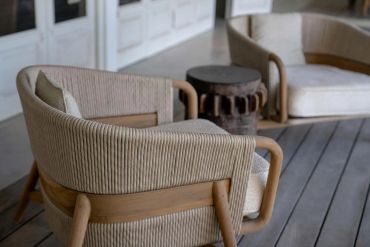 Two beige cushioned armchairs with wooden frames and a small round side table.