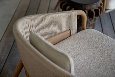 Close-up of a cozy chair with woven backrest and soft cushion.