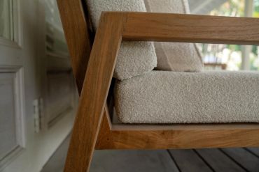 Close-up of a wooden armchair with textured beige cushions.