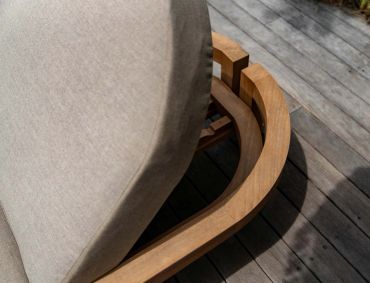 Close-up of a wooden chair base with beige cushion on wooden floor.