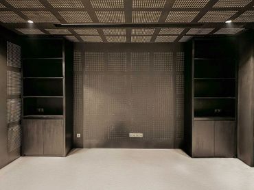 Modern minimalist room with perforated walls and ceiling panels.
