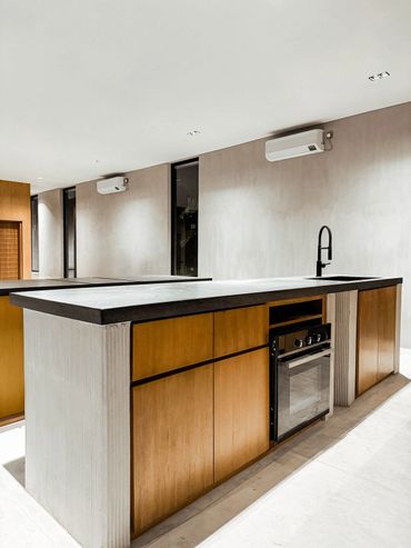Modern kitchen island with wooden cabinets and black countertop.
