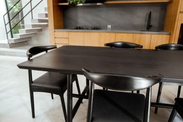 Modern black dining table with chairs in a minimalist kitchen.