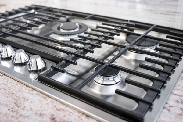 Close-up of a stainless steel gas cooktop with black grates and chrome knobs