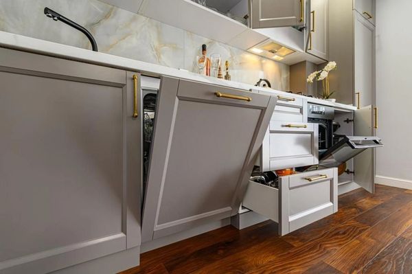 Modern kitchen cabinetry with open drawers and an angled dishwasher door featuring sleek gray finish