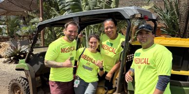 Four medical staff posing by an off-road vehicle outdoors.