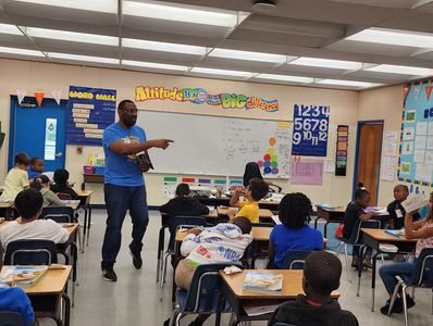Sahim distributing dictionaries to 3rd grade students.