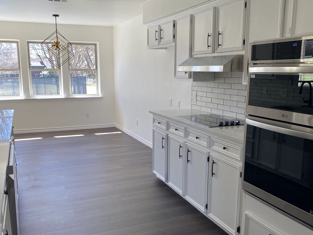 Modern kitchen with white cabinets and large windows.