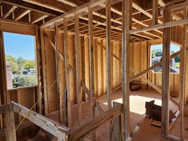 Interior of a wooden house under construction with framing and open windows.