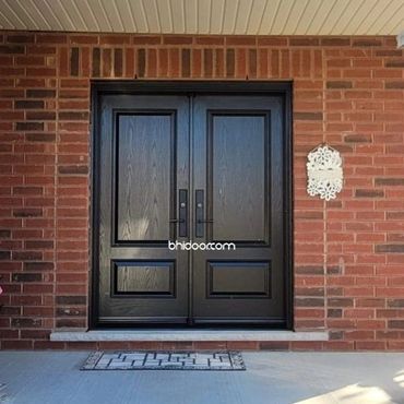 Elegant black double doors set in a red brick wall with a decorative white plaque.