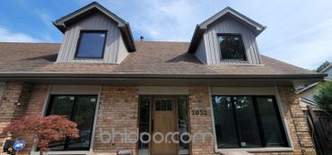 Front view of a brick house with two dormer windows and a wooden door.