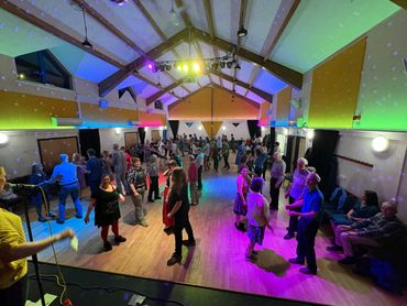 A lively dance event with colorful lights in a spacious hall.