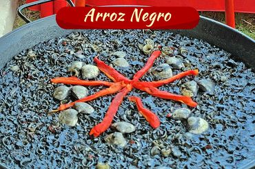 Traditional Arroz Negro with seafood and red pepper garnish.