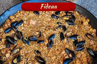 Fideua, a traditional seafood noodle dish with mussels and shrimp.