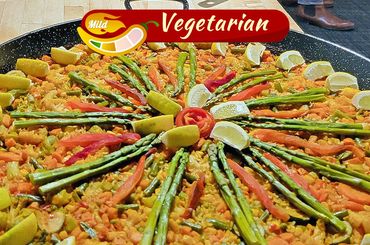 Colorful vegetarian paella with asparagus and lemon wedges.