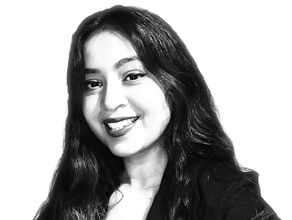 Black and white portrait of a smiling woman with long hair and a blazer.