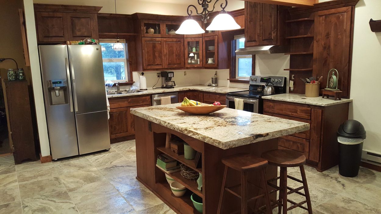 Pagosa cabinets, dark knotty alder custom kitchen cabinets, with open shelving and glass doors.
