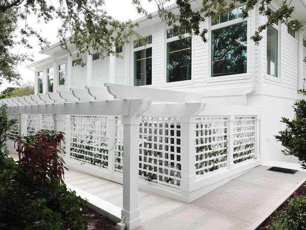 White house with a lattice fence and pergola.
