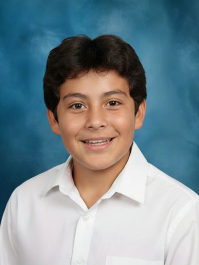 Smiling young boy in a white shirt against a blue backdrop.
