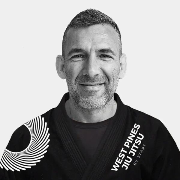 Man in a West Pines Jiu Jitsu uniform smiling.