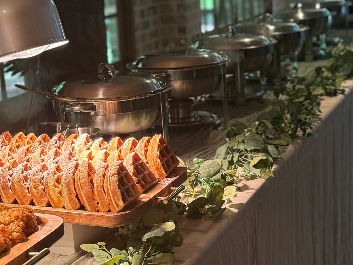 Waffles and fried chicken served buffet-style with decorative greenery.