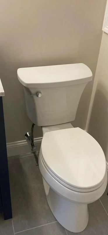 A clean white toilet next to a blue vanity in a modern bathroom.