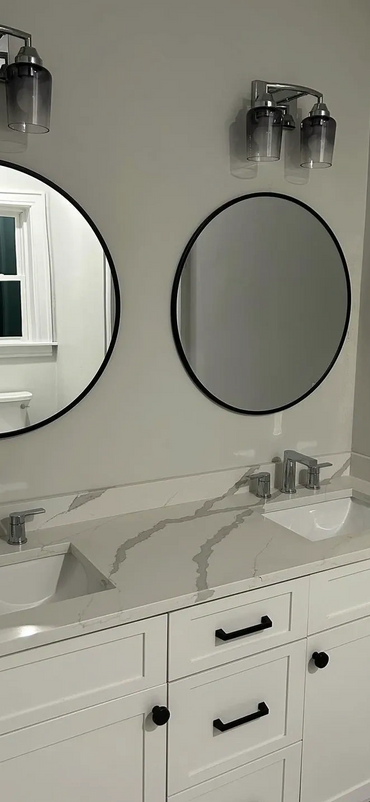 Modern bathroom vanity with dual sinks, round mirrors, and sleek lighting.