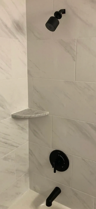 Modern shower with black fixtures and marble tiles.