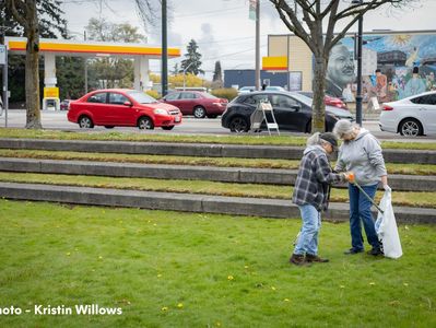 Two women, picking up litter in a park.