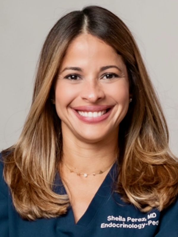Smiling female doctor in medical scrubs with name and specialization embroidered.