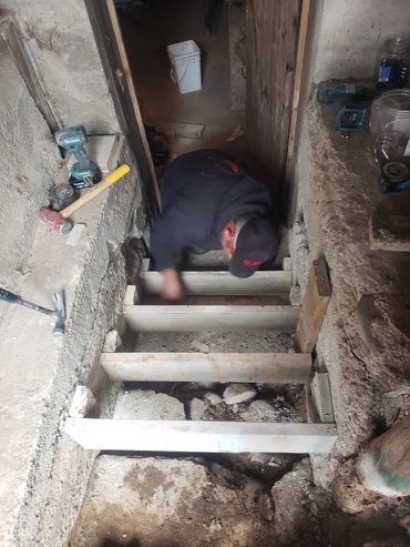 Person working on wooden floor frame in a rustic setting.