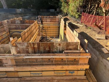 Construction workers prepare wooden forms for concrete foundation walls.