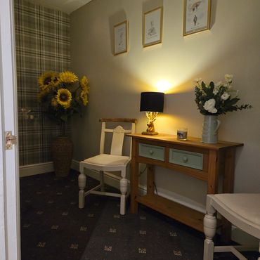 Cozy corner with wooden furniture, sunflower vase, and warm lighting.