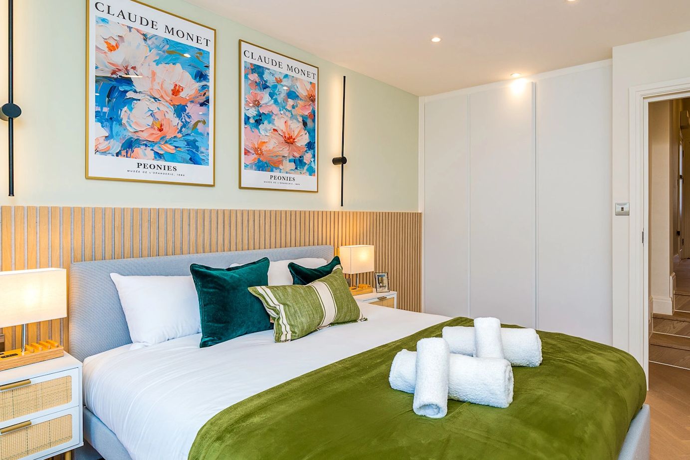 Modern bedroom with green accents and Monet artwork.