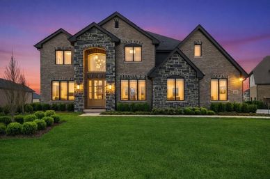 Elegant two-story house with stone and brick facade at dusk.