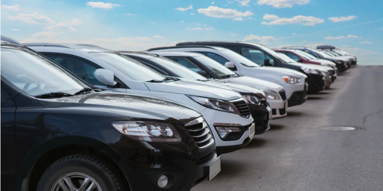 Row of parked cars lined up under a blue sky.