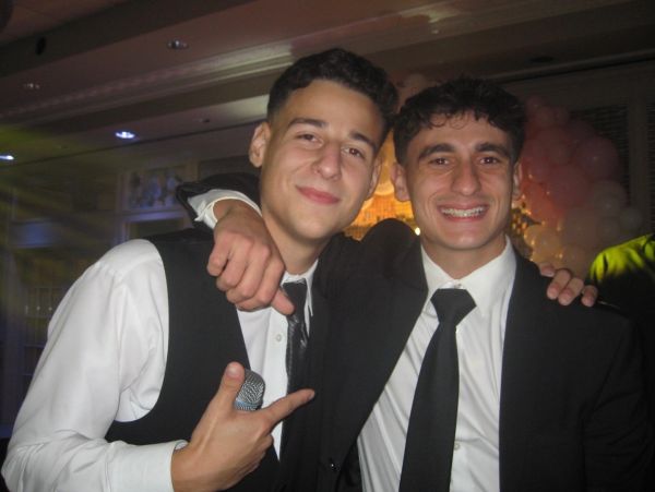 Two young men in suits smiling at the camera.