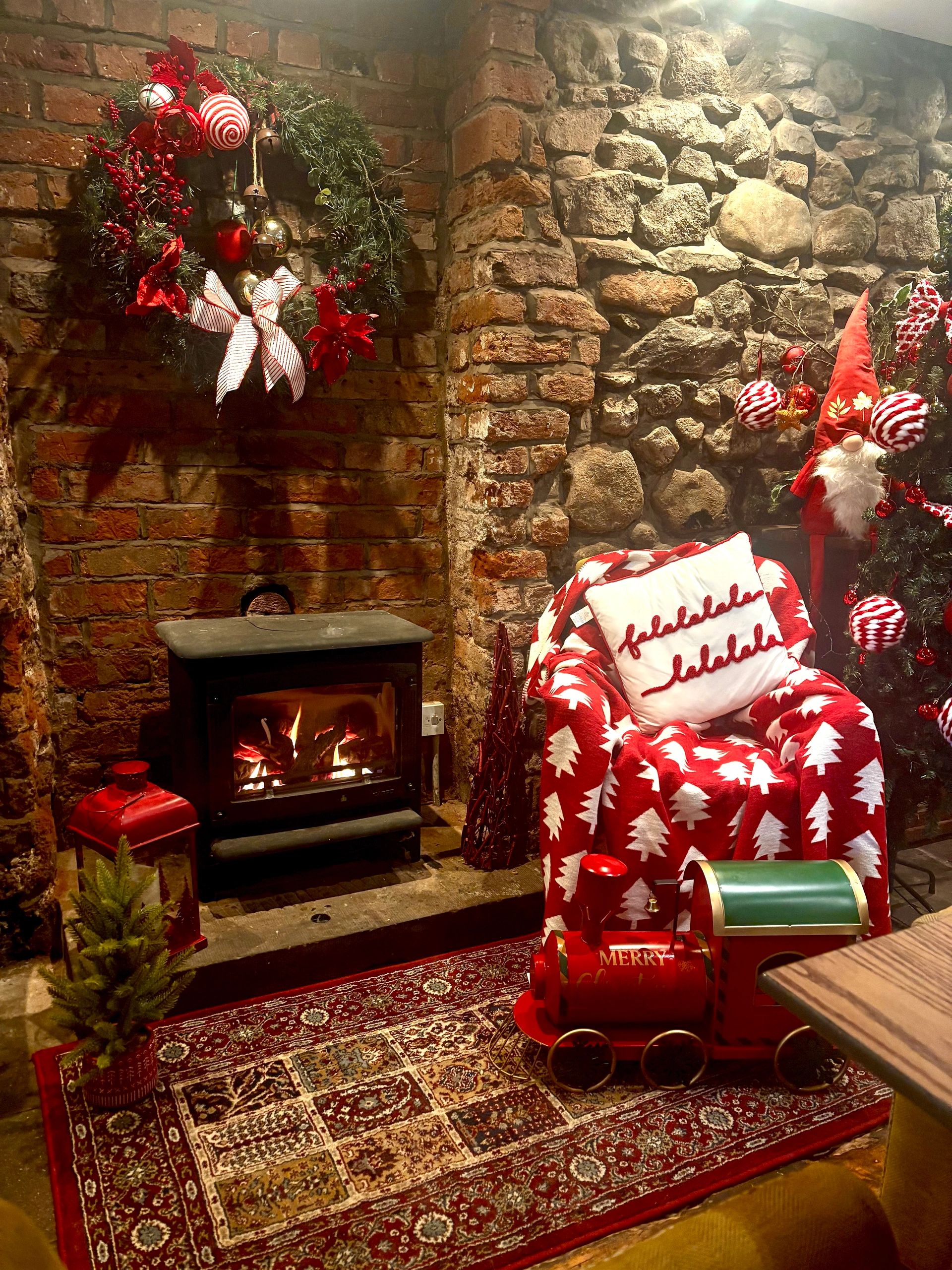 Cozy Christmas-themed room with fire and festive decorations.