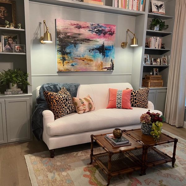 Cozy living room with white sofa and colorful cushions under abstract painting.