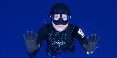 Freediver underwater at Apnea Academy Hong Kong, surrounded by deep blue water.