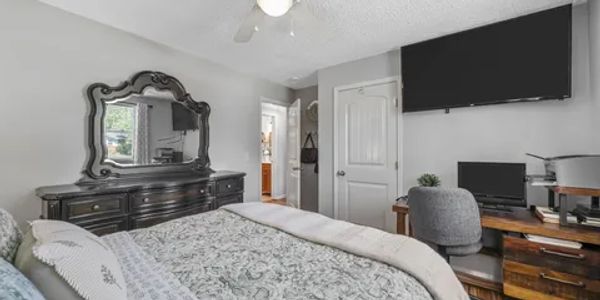 Cozy bedroom with elegant dresser, wall-mounted TV, and a work desk.