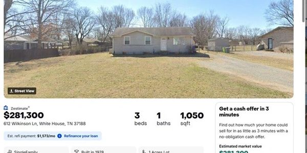 Single-story house with a large front yard in a suburban neighborhood.