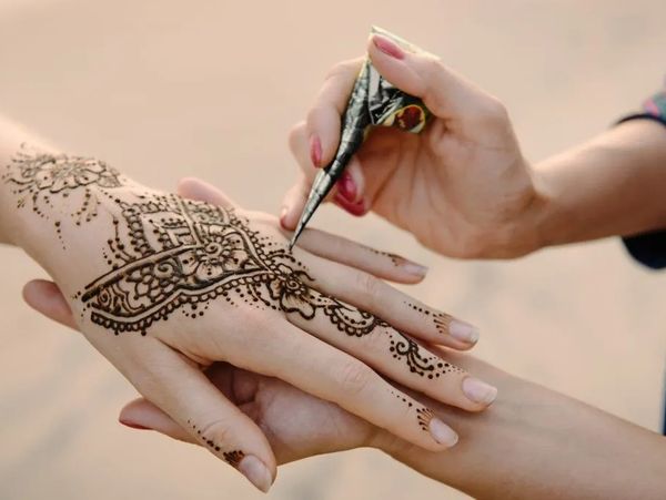 Woman applying Mehendi to bride