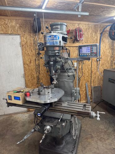 A milling machine in a workshop with digital readout and tools around.