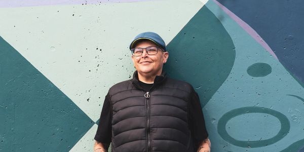 Person smiling against a geometric mural background.