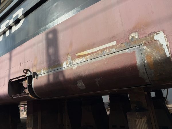 Close-up of a rusty and damaged ship hull section.